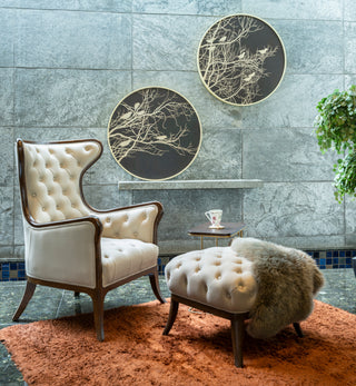 Decorative room with a white armchair, ottoman, and wall art on a tiled wall.
