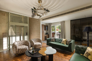 Living room with green leather sofa, patterned armchairs,multi colour center table and decorative coffee table.