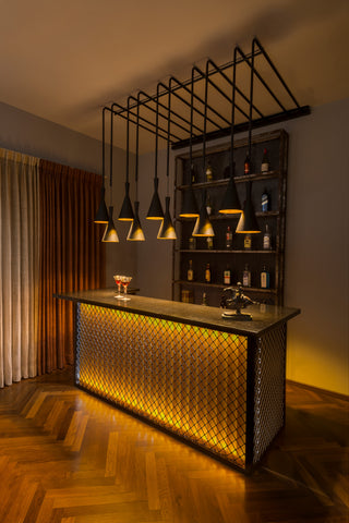 Modern bar setup with a metallic bar counter and shelves against a wall.