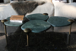 Set of green leaf-shaped coffee tables with a book on a gray sofa.