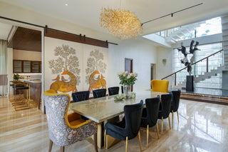 Modern dining room with a large table and chairs, featuring a decorative wall mural and stylish lighting.