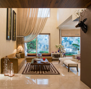 Modern living room with beige walls, large windows, and decorative elements.