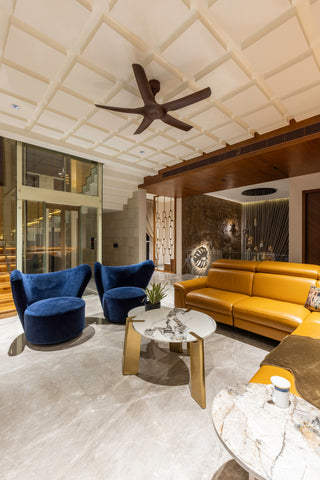 Modern living room with yellow sofa, blue armchairs, and marble coffee table.