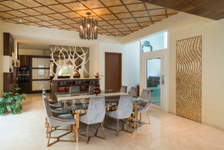 Modern dining room with a large Marble table and fabric chairs, featuring decorative wall art and a chandelier.
