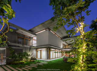 Modern house exterior at night with decorative lights and greenery