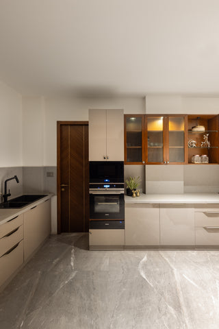 Modern kitchen with white cabinets, black appliances, and a marble floor.