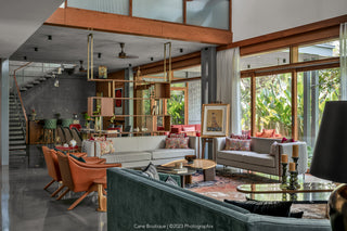 Modern living room with gray sofa, orange chairs, and large windows.