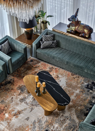 Modern living room with green sofas, a marble coffee table, and decorative elements.