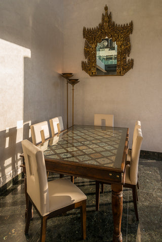 Dining room with a table and chairs, featuring a decorative mirror on the wall.