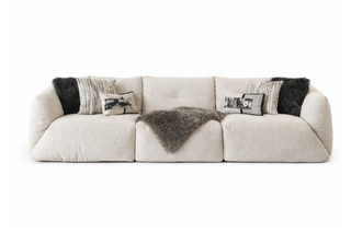 Beige sofa with decorative pillows and fur throw on a white background