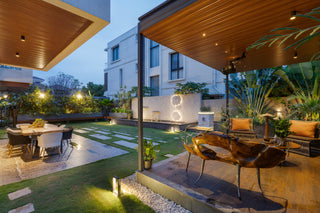 Modern outdoor patio with seating area, dining table, and garden lights.