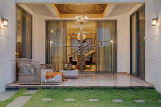 Modern patio with outdoor furniture and open sliding glass doors leading to a well-lit interior.
