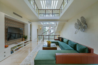 Modern living room with green and brown sofa, TV, and decorative elements.