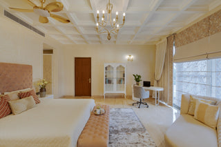 Luxurious bedroom with a large bed, sitting area, and decorative elements.