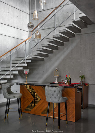 Wooden base bar table with marble top, and gray leather stools with decorative elements.