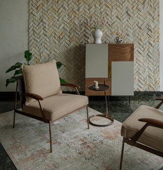 Modern living room with beige armchair, side table, and decorative cabinet against a patterned wall.