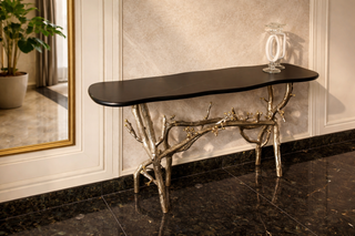 Decorative console table with unique metal legs against a wall with a mirror.