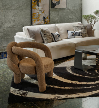 Modern living room with a beige sofa, textured armchair, and abstract art on the wall.