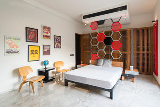 Modern bedroom with a bed, chairs, and decorative wall art.