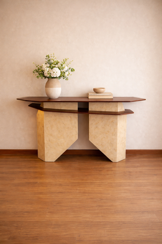 Modern console table with a vase of flowers and books against a beige wall.