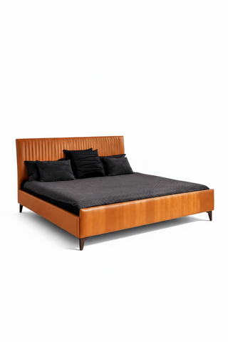 Bed with brown leather headboard and black bedding on a white background