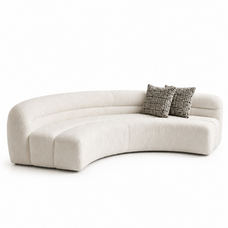 Curved beige sofa with patterned cushions on a white background