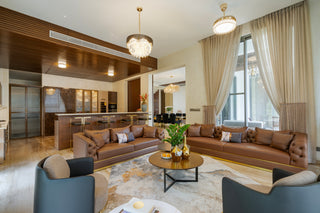 Modern living room with brown leather sofa, gray armchairs, and a coffee table.